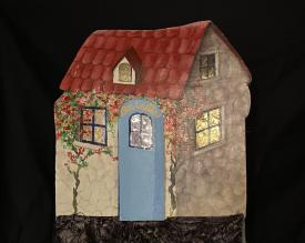 Maison à toit rouge, fenêtres dorée, porte bleue et une inscription "Chez Lorella"