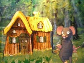 Ratapon devant une cabane au milieu d'un jardin, tournesol géant