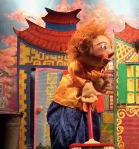 Youki avec un balais dans les mains, maisons à l'arrière-plan