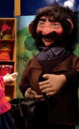 Homme brun, barbu et moustachu, vêtu d'une pantalon et d'une veste bruns