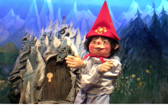 Léon, coiffé d'un bonnet magique devant une caverne fermée