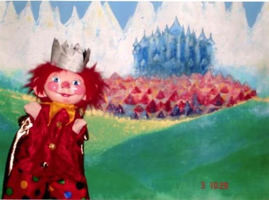 P'tit-Roi devant une colline verte, hautes montagne, ville et château en arrière-plan