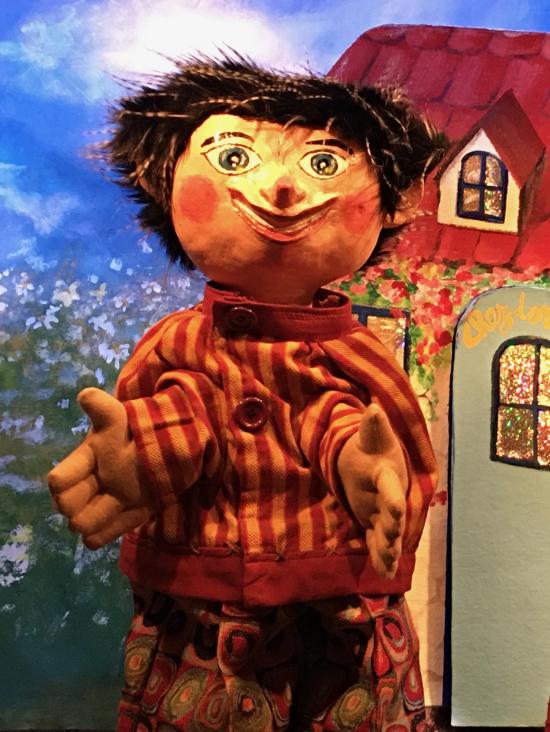 Jeune homme brun, vêtu d'un pantalon rouge à motifs et d'une veste à rayures rouges et jaunes