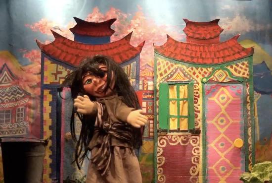 Jeune fille aux longs cheveux bruns décoiffés, vêtue d'une robe brun clair avec une ceinture à rayures