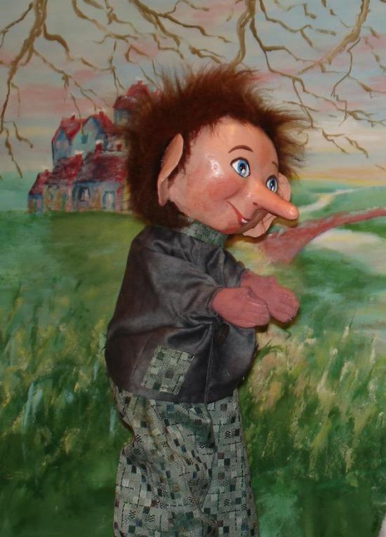 Garçon brun aux yeux bleus vêtu d'un pantalon gris à motifs, d'une veste grise et d'une écharpe à petits carreaux noirs et blancs