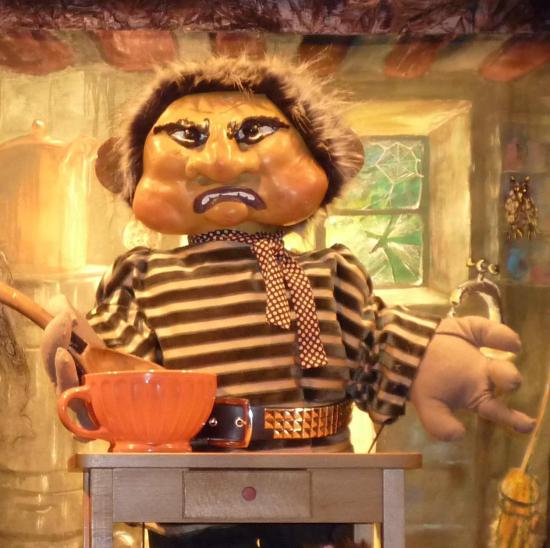 Croc'Peton à table, devant un bol orange, avec une cuiller à la main