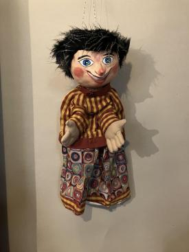 Tibougon joyeux, jeune garçon aux cheveux noirs, vêtu d'un pantalon bariolé et d'une veste à rayures jaunes et brunes