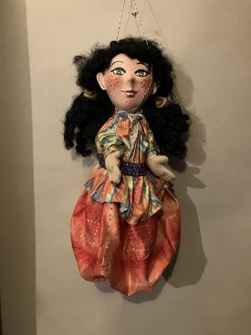 Jeune ville noiraude aux yeux verts, avec des taches de rousseur, vêtue d'un pantalon large orange et d'une casaque multicolore