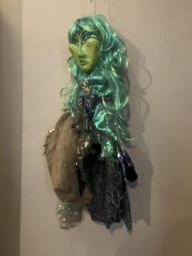 Sirène au visage et cheveux verts, vêtue d'une robe à dessins d'écailles