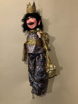 Roi aux cheveux et moustache noirs, vêtu d'un habit brillant et d'une cape dorée, coiffé d'une couronne d'or