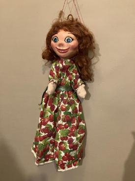 Jeune fille rouquine aux yeux bleus, vêtue d'une salopette à motifs de fruits