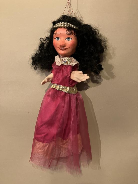 Jeune fille brune aux yeux bleus, vêtue d'une robe rose à ceinture dorée