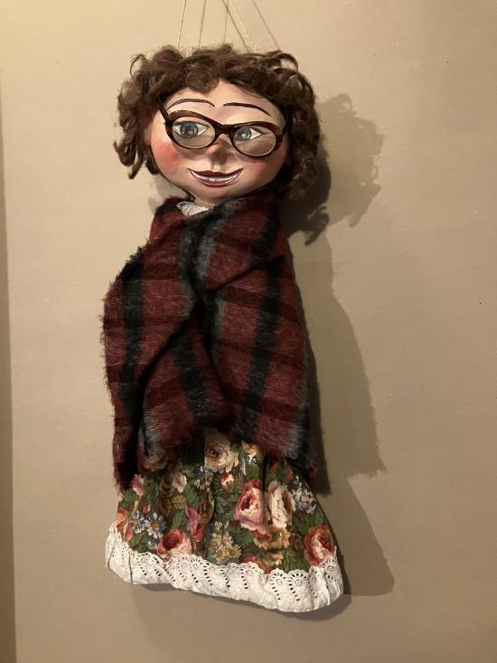 Femme brune à lunettes, vêtue d'une robe à fleurs et d'un châle