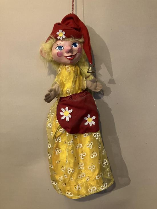 Jeune fille vêtue d'une robe dorée avec motifs de marguerites, d'une tablier rouge et d'un bonnet à clochette route