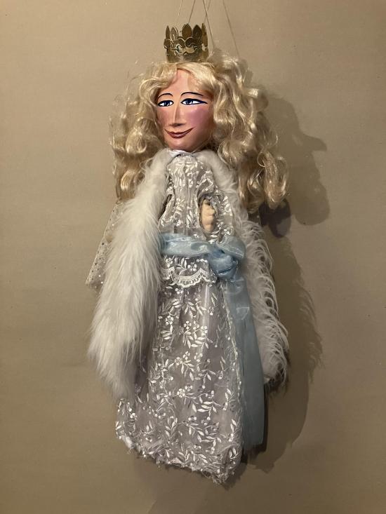 Fée blonde vêtue d'une robe blanche et d'une capeline en plumes, coiffée d'une petite couronne dorée