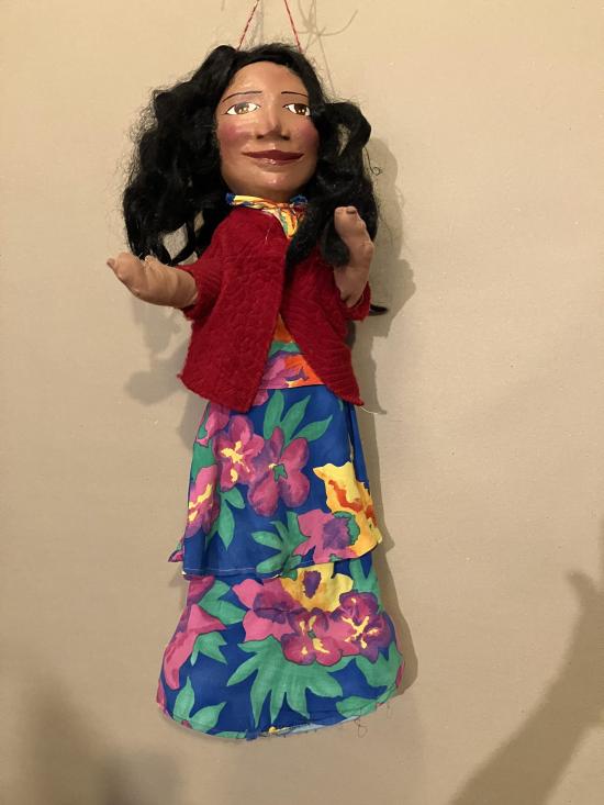 Femme aux longs cheveux bruns vêtue d'une robe à fleurs et d'un gilet rouge