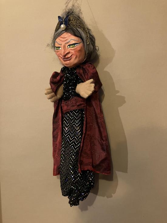 Vieille femme aux cheveux gris, vêtue d'une robe noire à pois brillants et d'une cape brune