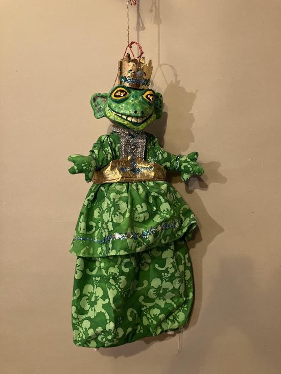 Grenouille vêtue d'un pantalon et d'une veste verts, coiffée d'une couronne d'or