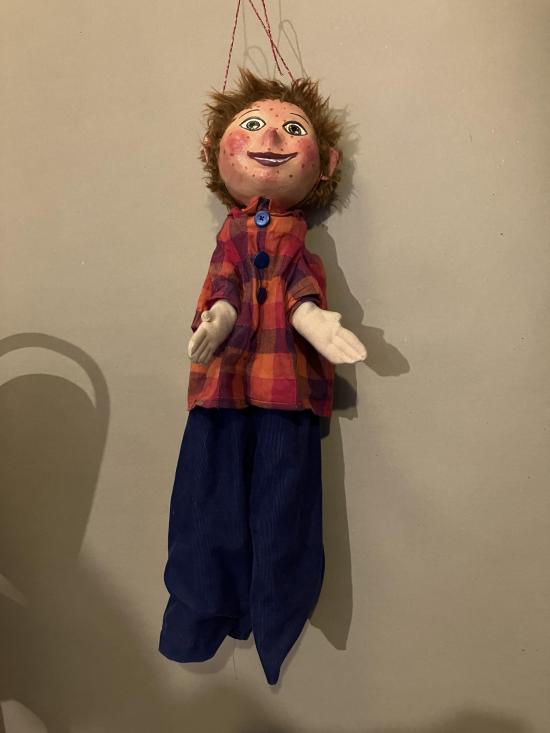 Jeune homme roux vêtu d'un pantalon bleu foncé et d'une veste à carreaux rouges