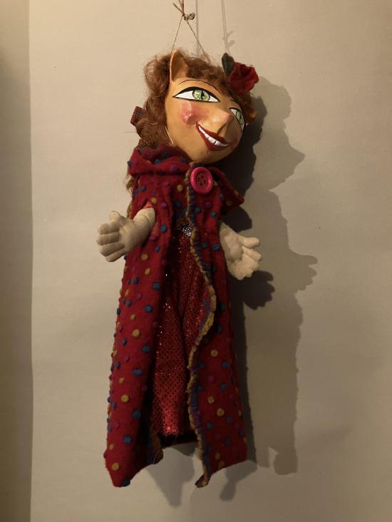 Fille châtain clair aux yeux verts, vêtue d'une robe et d'une longue cape rouges