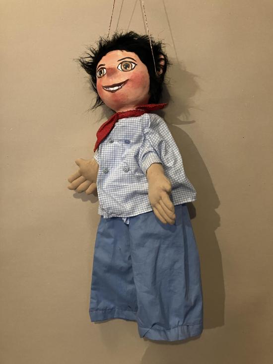 Jeune homme brun aux yeux bruns, vêtu d'un pantalon bleu clair et d'une chemise à petits carreaux bleus et blancs