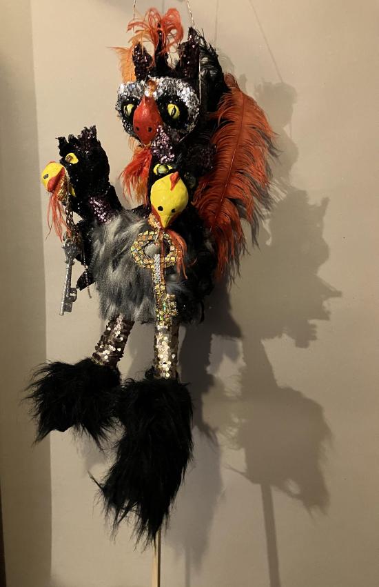 Griffon à trois têtes, avec des plumes noires et oranges, il tient une clé en matières précieuses