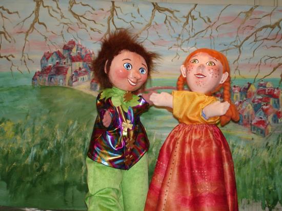 Mélodie et Pierrot vêtu d'habits printaniers dans la prairie, un village en arrière-plan