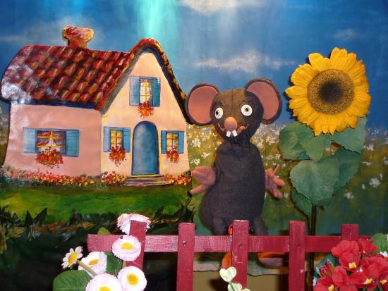 Ratapon devant une maison sise au milieu d'un jardin, tournesol géant