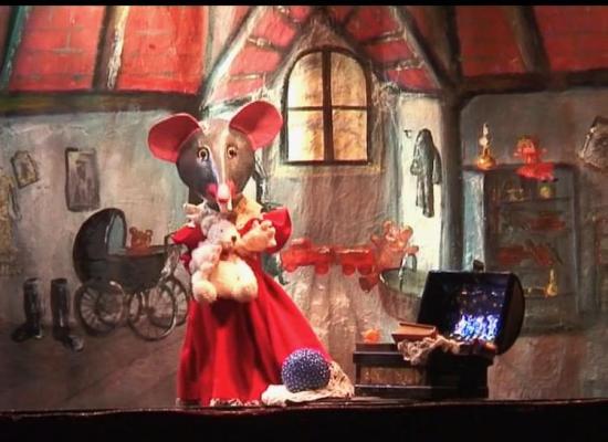 Petite Souris dans son grenier, à côté d'un coffre ouvert duquel dépasse un livre et une splendide pierre bleue devant elle