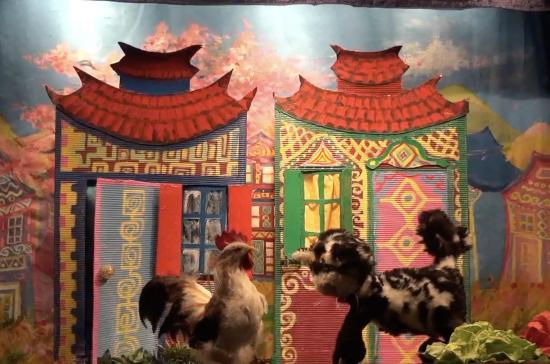 Un chat et une poule devant deux maisons colorées