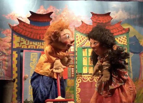 Youki avec un balais dans les mains et sa soeur Lilou devant des maisons colorées