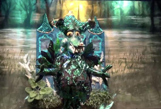 Dragon vert devant un marais au milieu duquel se trouve un beau château bleu