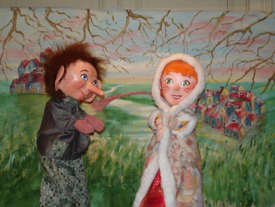 Pierrot avec son long nez et Mélodie enveloppée d'un manteau, dans la campagne, avec deux villages séparés par un pont au loin