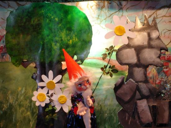 Lutin avec une grande marguerite dans la main, à côté du profil de la reine pétrifiée