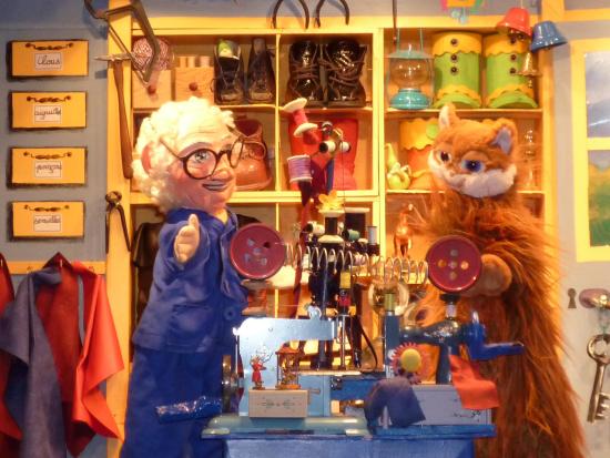 Léon dans son atelier de cordonnier avec Pat'Minouche; une grosse machine à coudre trône et des étagères sont remplies de bottines et de matériel de cordonnerie