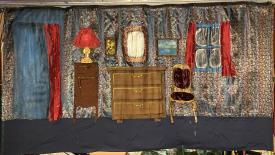 Salon avec une porte, une fenêtre, une tapisserie brillante, des rideaux rouges et quelques meubles