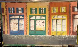 Rue bordée de boutiques : pâtisserie, épicerie, quincaillerie