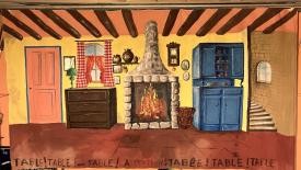 Cuisine chaleureuse, dans les tons jaune, ocre et rouge, avec un feu dans l'âtre et un escalier sur la droite