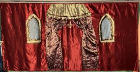 Tentures rouges, porte monumentale et fenêtres en ogive