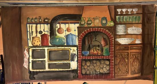 Cuisine avec cheminée allumée et un grand poêle; une marmite pend à une crémaillère dans la cheminée, le poêle est couvert de casseroles