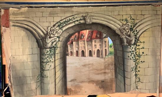 Porte de bourg avec une arche voûtée, place du bourg en arrière-plan